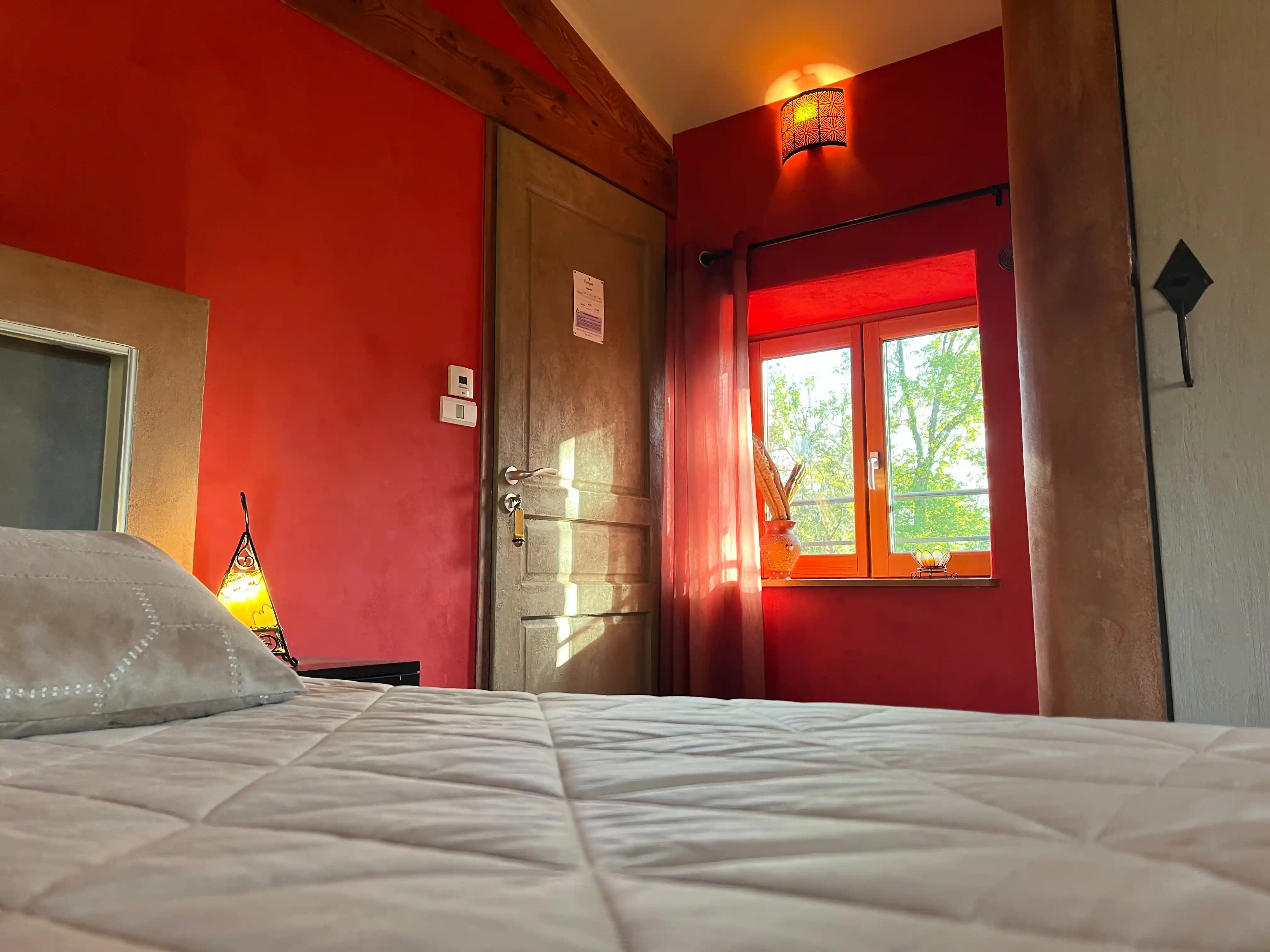 Lit de la Chambre Marocaine baigné de lumière naturelle avec vue sur les arbres
